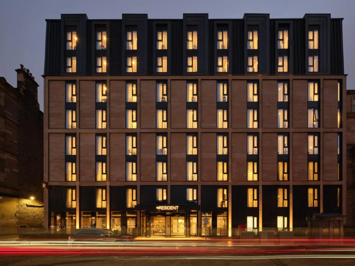 a building with illuminated windows on a city street at The Resident Edinburgh in Edinburgh
